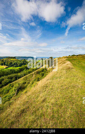 Una vista lungo i bastioni di Uley Bury Iron Age Hill forte verso Downham collina nel Cotswolds, Inghilterra Foto Stock