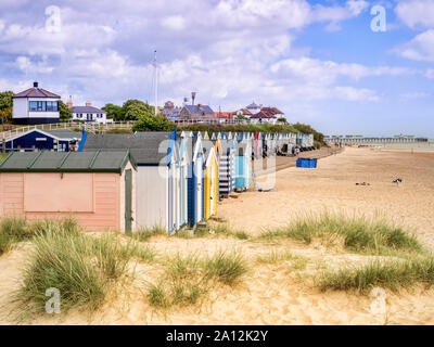 17 Giugno 2019: Southwold, Suffolk, Regno Unito - la spiaggia e le capanne, con il molo dietro a Southwold, Suffolk Foto Stock