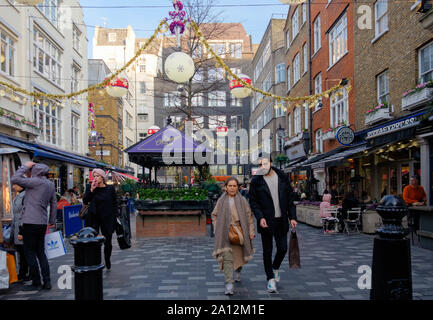 Persone shop, Mangiare & bere e socializzare presso la piazza centrale, San Cristoforo, luogo appartato lontano high-end di vicolo fuori Oxford St. al tempo di Natale. Foto Stock