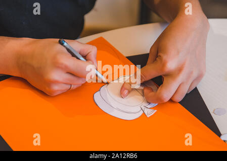 La donna le mani vicino la zucca di disegno su carta colorata Foto Stock