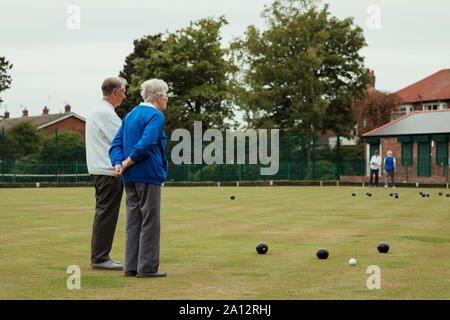 Una vista posteriore colpo di senior adulti agli spettatori un prato bowling gioco, in piedi con le mani dietro la schiena. Foto Stock