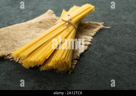 Materie spaghetti legato con una corda su una texture nera dello sfondo. Copia dello spazio. Foto Stock