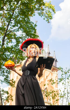 Strega legge libro di magia e mantiene le vacanze zucca di Halloween Foto Stock