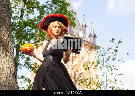 Strega legge libro di magia e mantiene le vacanze zucca di Halloween Foto Stock