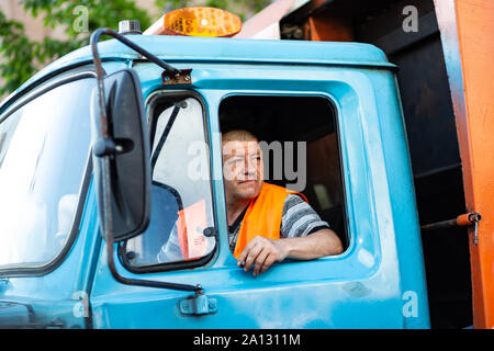 Kiev, Ucraina, 26 maggio 2019. Garbage camionista fuma in cabina di autocarro Foto Stock