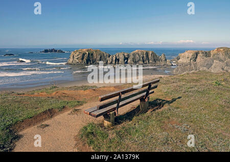 Un banco di solitario si siede a un si affacciano lungo la Oregon Pacific Coast in città di Bandon, Oregon. Foto Stock