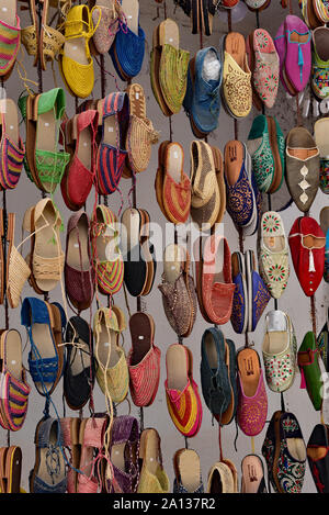 Scarpe colorate per la vendita appeso al di fuori di un negozio, un molto tipica scena in tutta la città di Essaouira, Marocco, Africa del Nord. Foto Stock
