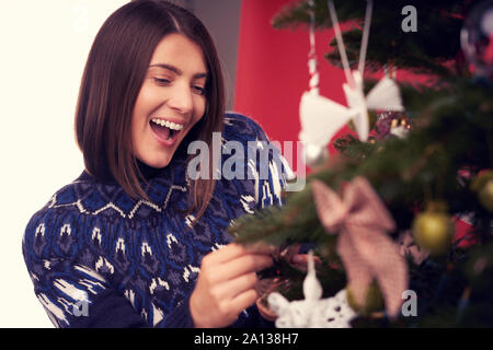 Donna adulta decorare albero di Natale su sfondo rosso Foto Stock