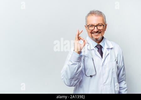 Allegro medico matura in posa e sorridente alla fotocamera, la sanità e la medicina. Foto Stock