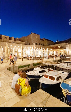 Dubrovnik Vacanze: turista giovane seduto nel vecchio porto di sera, Dubrovnik Città Vecchia, sito patrimonio mondiale dell'UNESCO, Dubrovnik Croazia Europa Foto Stock