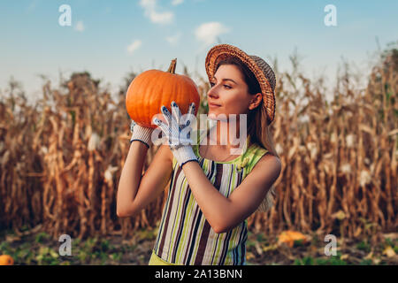 Raccolto di zucca. Donna giovane agricoltore picking raccolto autunnale di zucche in azienda. L'agricoltura. Il ringraziamento e la preparazione di Halloween Foto Stock