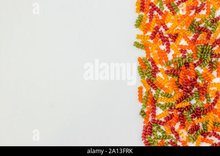 Fusilli pasta multicolore su uno sfondo bianco, orientamento orizzontale, spazio di copia Foto Stock