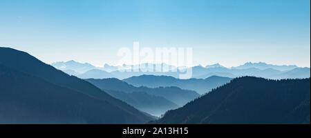 Le catene montuose uno dietro l'altro in controluce, vista del panorama alpino dal vertice di Breitenstein, Fischbachau, Baviera, Germania Foto Stock