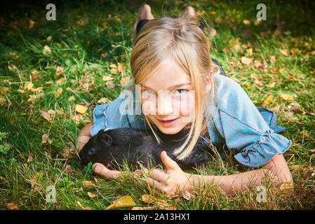 Bambina cute giocare con animale domestico porcellino d'India all'aperto su erba verde Foto Stock