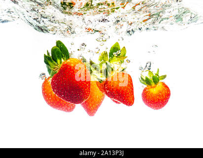 Le fragole di cadere in acqua causando bolle tutto intorno. Cibo sano concetto Foto Stock