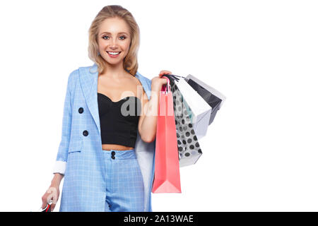 Bellissima ragazza con serrature di Hollywood, classic make-up in un elegante vestito blu e borse per lo shopping. Bellezza viso e corpo. Foto Stock