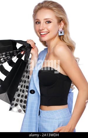 Bellissima ragazza con serrature di Hollywood, classic make-up in un elegante vestito blu e borse per lo shopping. Bellezza viso e corpo. Foto Stock