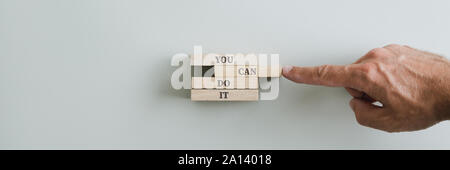 Ampia vista immagine del maschio montaggio a mano un è possibile farlo firmare scritto su picchetti di legno. Su sfondo beige. Foto Stock