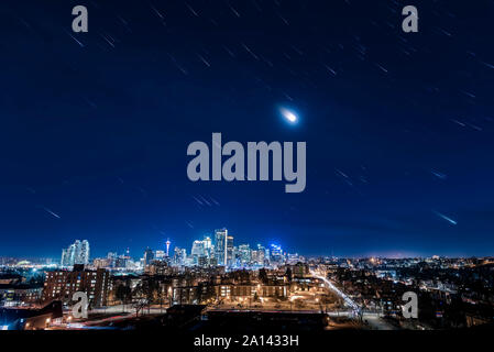 Tracce stellari di Orion, la luna e le stelle di inverno sopra il centro cittadino di Calgary, Canada. Foto Stock