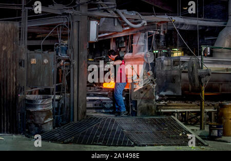 27 sett 2019 Kokomo Indiana USA; un lavoratore mix di vetro fuso in progetti prima di alimentarlo in una macchina per fare un foglio di vetro macchiato in un bicchiere Foto Stock