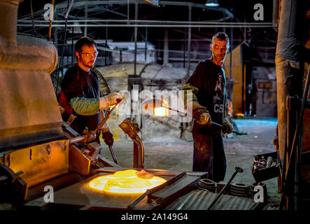 27 sett 2019 Kokomo Indiana America; operai in una fabbrica di vetro di guardare una crescente pila di vetro fuso, che sarà ora roteato insieme ed eseguire attraverso th Foto Stock