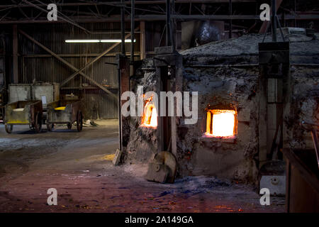 27 sett 2019 Kokomo Indiana USA; un vecchio forno si illumina di rosso caldo, che fonde il vetro di molti colori, utilizzato per rendere il vetro macchiato fogli in corrispondenza della più antica fa di vetro Foto Stock