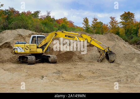 Un Kobelco via hoe parcheggiato in una spiaggia di sabbia e ghiaia pit nelle Montagne Adirondack, NY all'inizio dell'autunno. Foto Stock