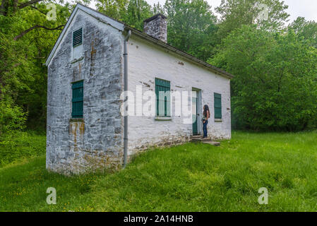 Donna in piedi da bloccare i detentori casa bianca con persiane verdi e porta a Chesapeake e Ohio Canal Foto Stock