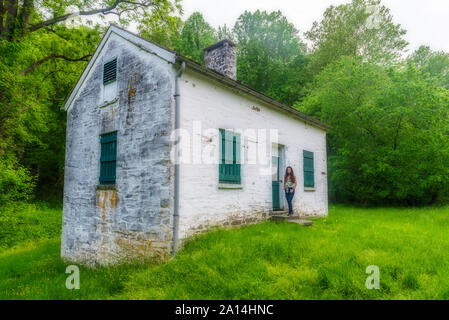 Donna in piedi da bloccare i detentori casa bianca con persiane verdi e porta a Chesapeake e Ohio Canal Foto Stock