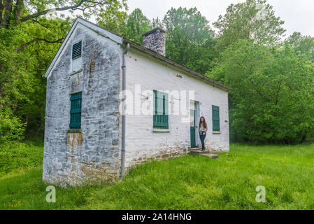 Donna in piedi da bloccare i detentori casa bianca con persiane verdi e porta a Chesapeake e Ohio Canal Foto Stock