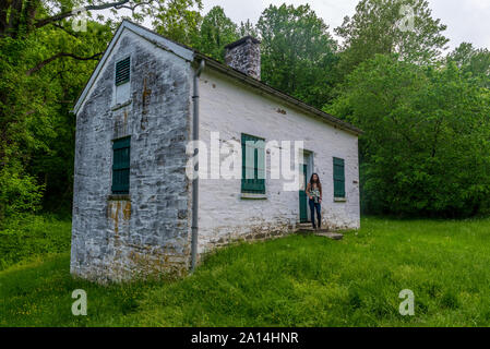 Donna in piedi da bloccare i detentori casa bianca con persiane verdi e porta a Chesapeake e Ohio Canal Foto Stock