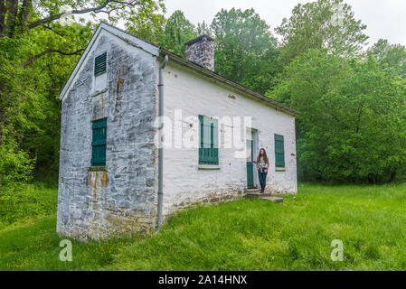 Donna in piedi da bloccare i detentori casa bianca con persiane verdi e porta a Chesapeake e Ohio Canal Foto Stock