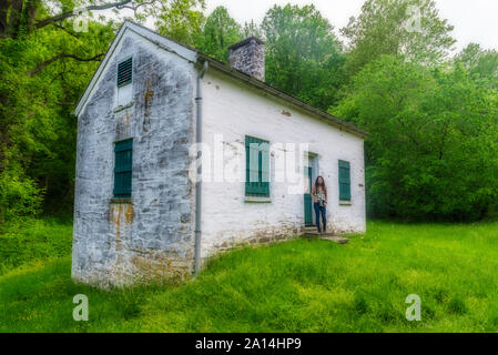 Donna in piedi da bloccare i detentori casa bianca con persiane verdi e porta a Chesapeake e Ohio Canal Foto Stock