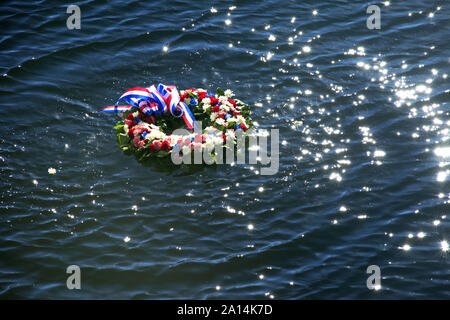 Una corona di fiori viene posto in acqua per informarla della vite perdute durante gli attacchi di Pearl Harbour. Foto Stock