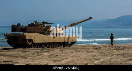 Stati Uniti Soldato dell'esercito guide un M1A1 Abrams battaglia principale serbatoio sulla spiaggia in Corea del Sud. Foto Stock