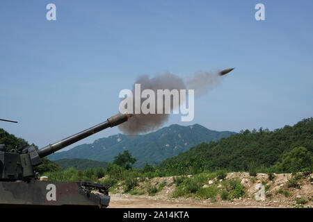 Un 155mm rotondo è sparato da un M109A6 Paladin semoventi obice. Foto Stock