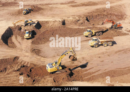 Escavatori che caricano il terreno su un trasportatore articolato Trucks, immagine aerea. Foto Stock