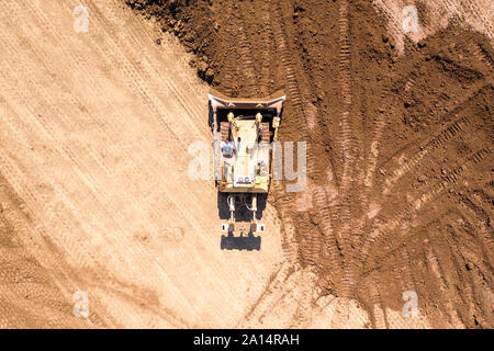 Bulldozer spingendo grandi quantità di terreno fresco, immagine aerea. Foto Stock