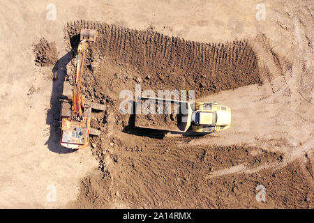 Escavatore terreno di caricamento su un trasportatore articolato carrello, superiore dell'antenna verso il basso Foto Stock