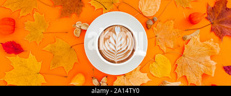 Autunno piatto composizione laici con foglie secche ghirlanda di telaio e caffè latte cup sul bold orange Colore di sfondo. Creative autunno, ringraziamento, caduta, ha Foto Stock