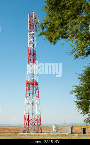 5G antenna per la connessione internet ad alta velocità di distribuzione. 5G di ripetitori fuori città. Colori luminosi rosso e bianco. Foto Stock