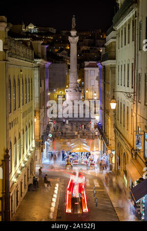 Il traffico di persone e pasti al fresco sulla Calcada do Carmo street e la colonna e la statua di Dom Pedro IV presso la piazza Rossio a Lisbona di notte. Foto Stock