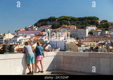 Due turisti di Arco de Rua Augusta (Rua Augusta Arch) piattaforma di osservazione con il castello Sao Jorge e vista sulla città dietro a Lisbona, Portogallo. Foto Stock