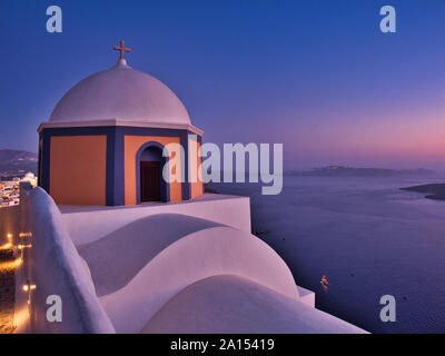 Vista pittoresca della tradizionale cattedrale a cupola sopra il mare tranquillo al tramonto in Fira Santorini Grecia Foto Stock