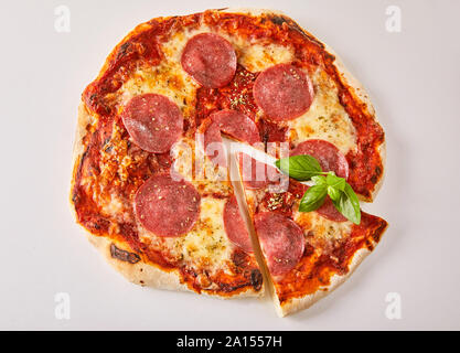 Vista aerea di un salame tradizionale pizza italiana con una singola fetta tagliata isolato su bianco per il menu pubblicità Foto Stock