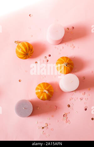 Composizione di Halloween di rosa candele, zucche di piccole dimensioni e il decor glitter su sfondo rosa. Vista superiore, posto per il testo. Foto Stock