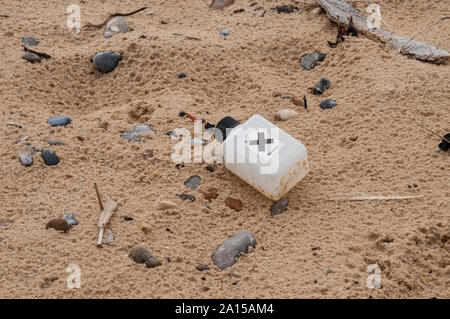 Una plastica bootle con una etichetta di pericolo riscontrato lavato fino a una spiaggia di Suffolk Foto Stock