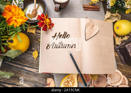 Autunno insieme di foglie di giallo e fiori. Notebook con pagine aperte sul tavolo. Spazio per il testo. Vista dall'alto. Concetto Ciao autunno Foto Stock