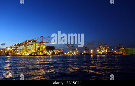 KAOHSIUNG, Taiwan -- Giugno 2, 2019: contenitori vengono caricati sulle navi nel porto di Kaohsiung all'imbrunire Foto Stock