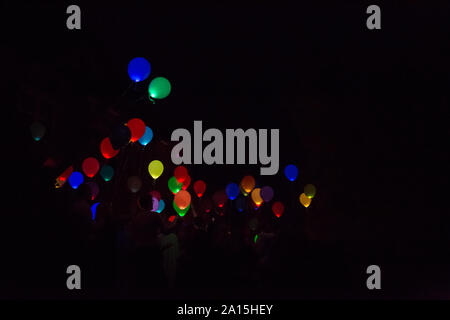 Persone che lasciate colorate, incandescente palloncini volare nel cielo notturno. Foto Stock